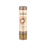 Monin L'Artiste caramel flavoured sauce in 150ml cylindrical tube with cream label, warm amber swirl motif and rust-orange accent bands, on white background