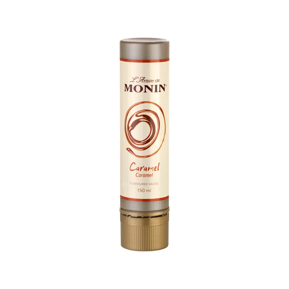 Monin L'Artiste caramel flavoured sauce in 150ml cylindrical tube with cream label, warm amber swirl motif and rust-orange accent bands, on white background