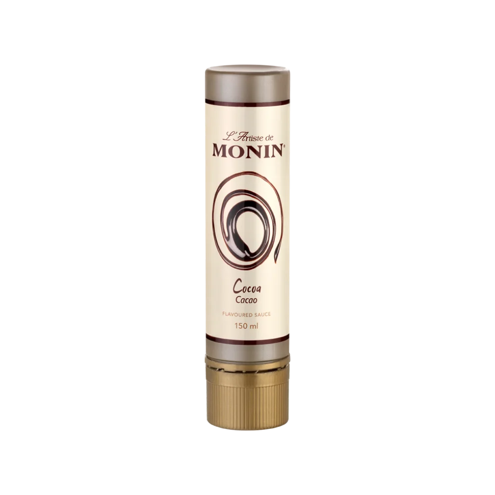 Monin L'Artiste cocoa flavoured sauce in 150ml cylindrical tube with cream label, dark brown swirl motif and gold metal dispensing tip, on white background